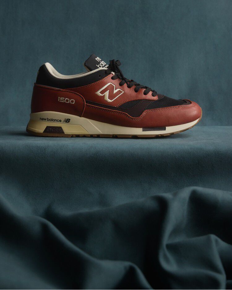 A New Balance Made in UK sneaker sitting in a flowing blue fabric studio backdrop. 