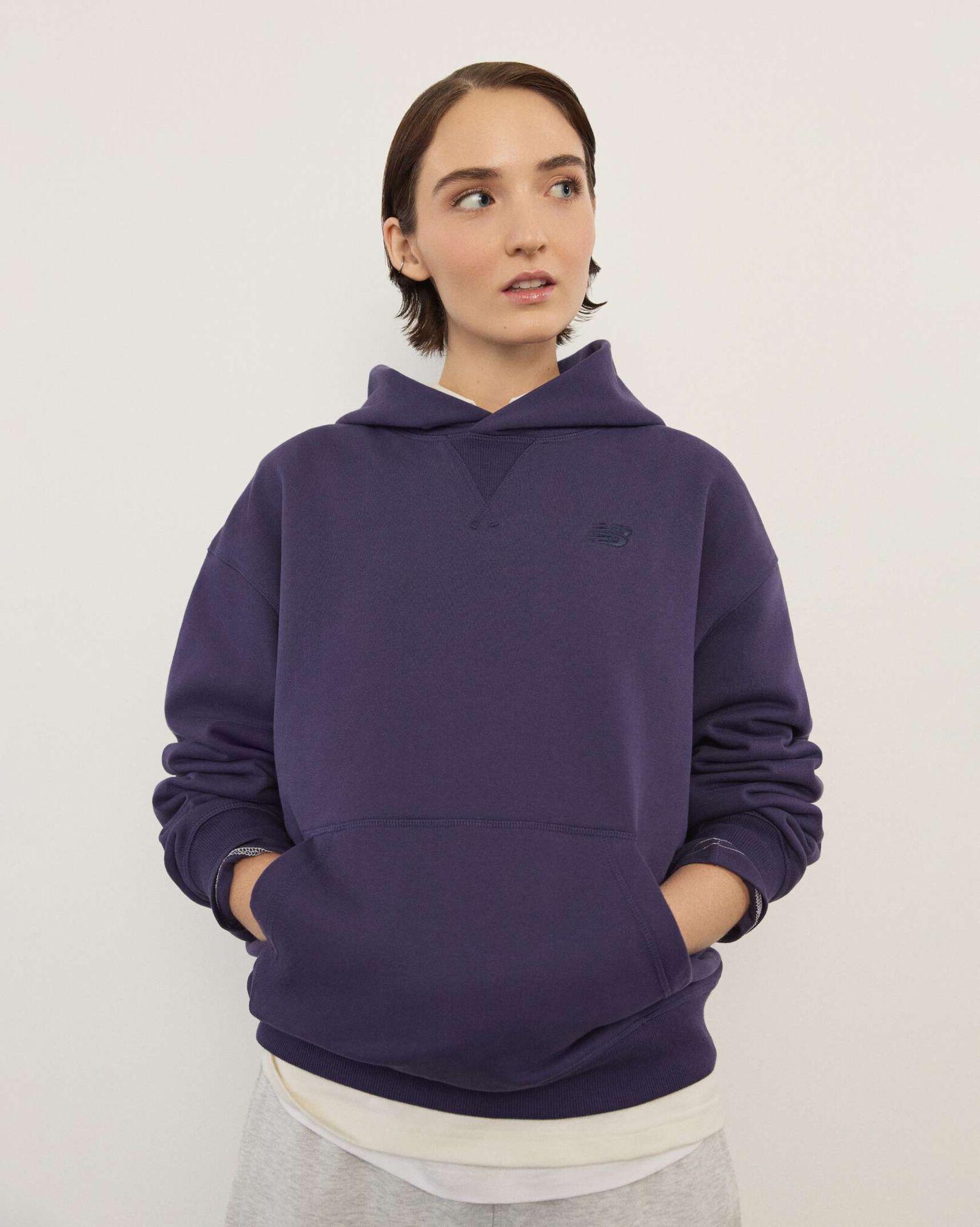 A woman wearing New Balance standing in front a white wall.