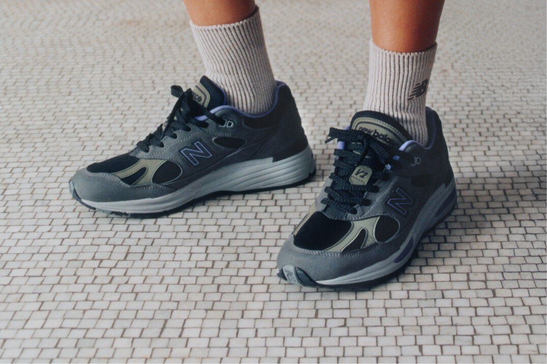 A pair of New Balance Made in UK sneakers sitting on a concrete floor.